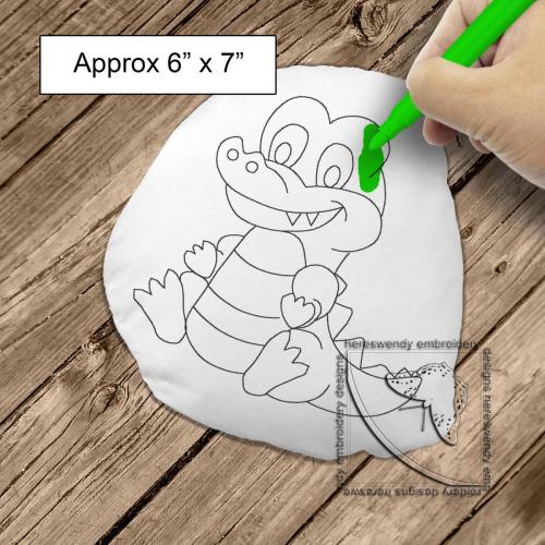 Image of design DD003 of a smiling crocodile cuddly colouring in stuffie, with child's hand colouring it in with size label saying it is approximately 6" x 7"